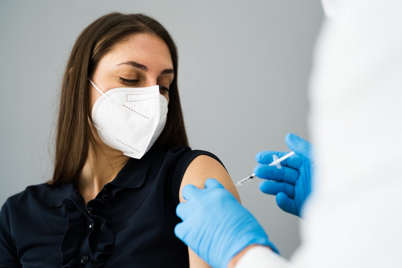 Mujer con máscara siendo vacunada