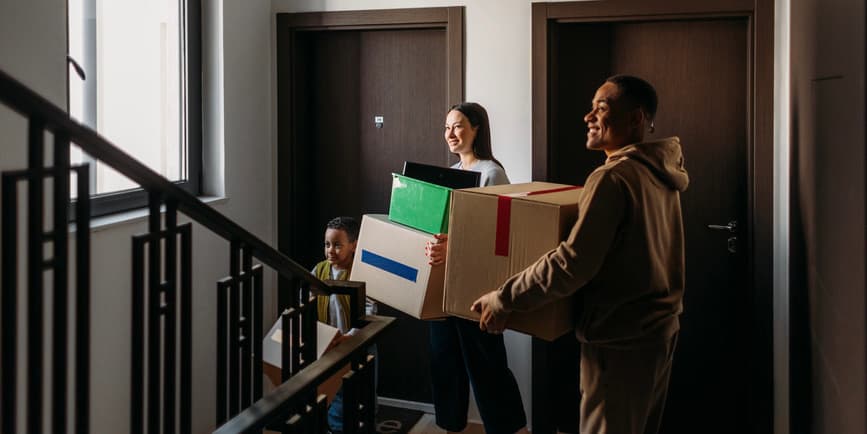 A family of three moving into new apartment together, carrying boxes with different stuff