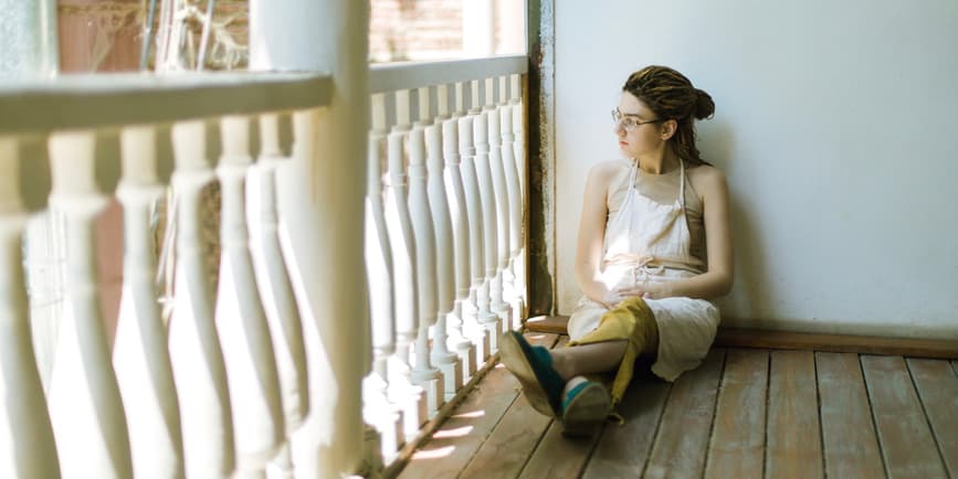 Young woman in a work apron on a sunlit balcony