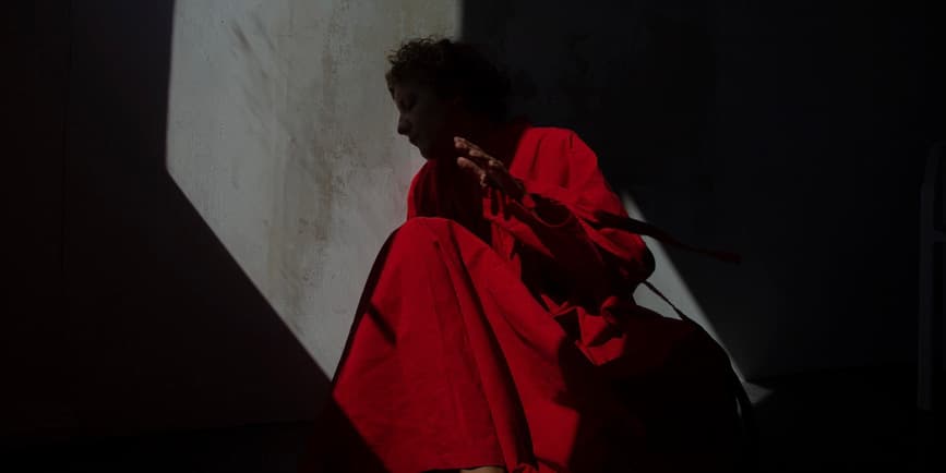 Woman in red dress moving in red dress in the sunlight.