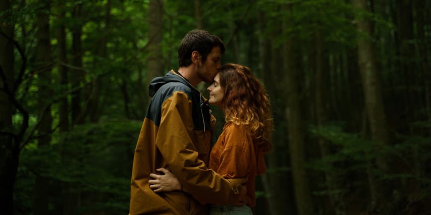 Portrait of a loving white couple hugging and kissing in beautiful. dense forest.