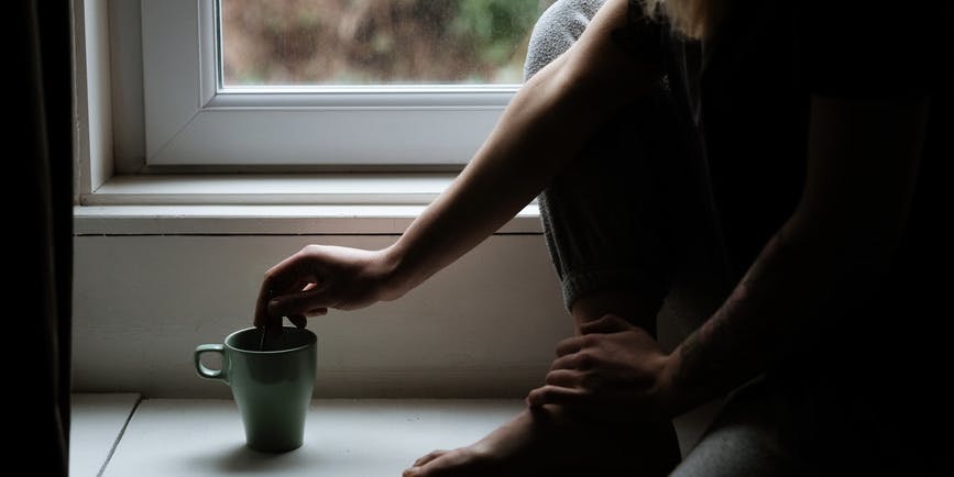 Sleepy Blonde Woman Sitting In The Window Taking A Cup Of Coffee In The Morning