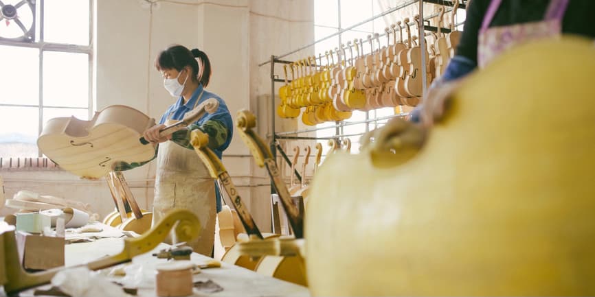 A Chinese violin maker working and making a cello in her workshop.