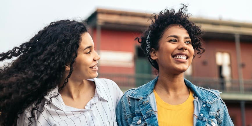 Young Latina women with curly hair walking around the city smiling.