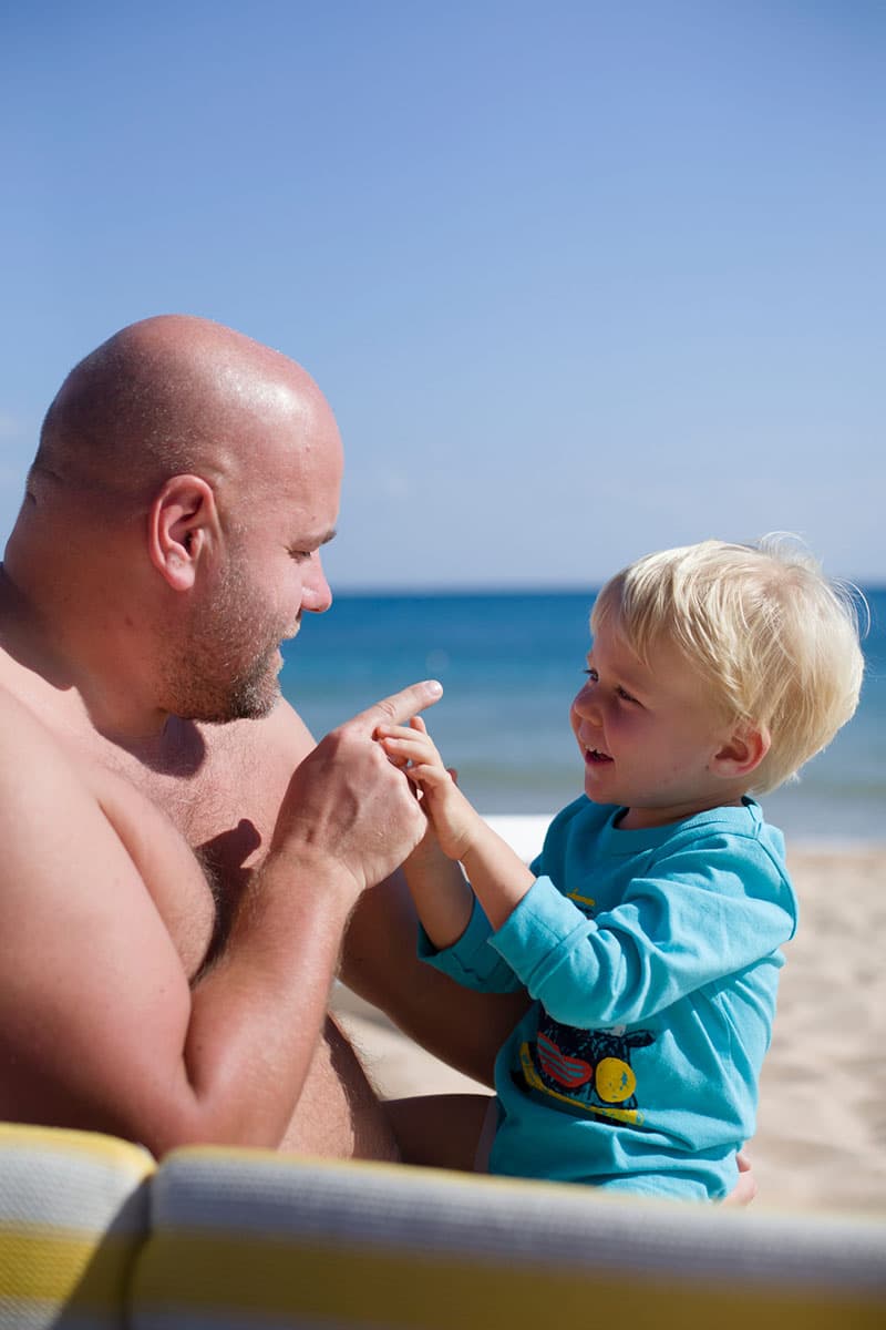 Overweight father playing with his son at the beach