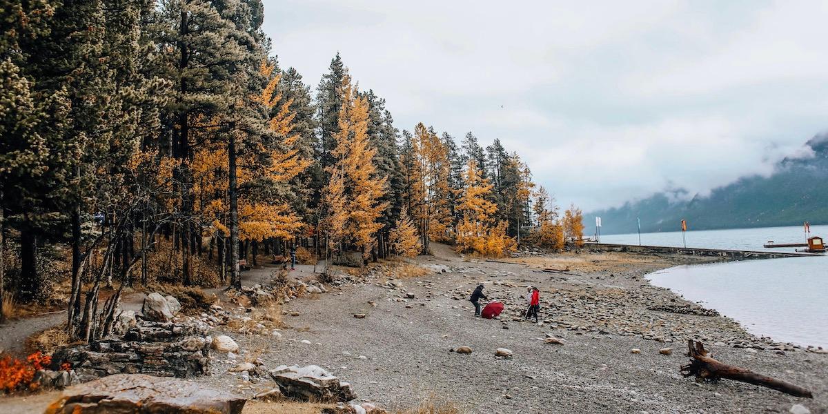 Faraway shot of two people on a lakeshore in autumn.