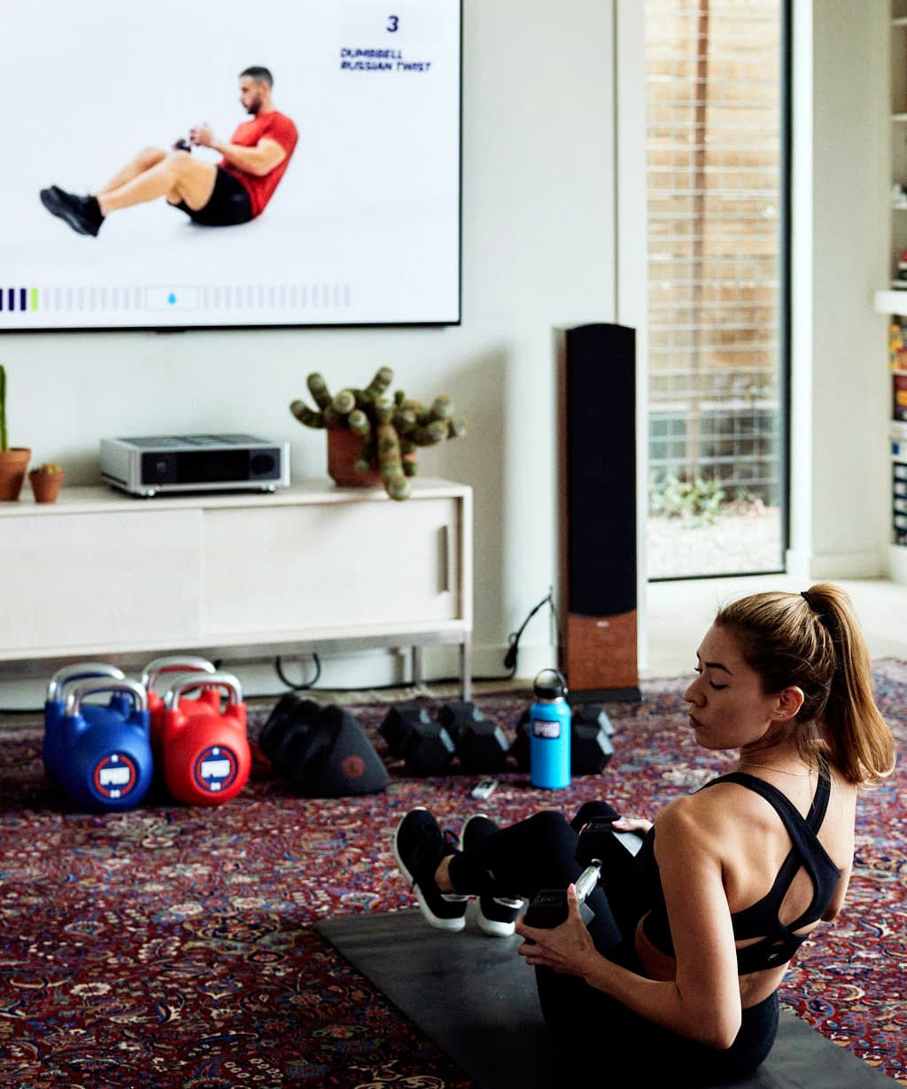 Woman working out at home with F45 Training fitness content