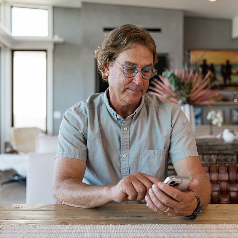 Middle-aged man sitting at his home's kitchen counter on phone