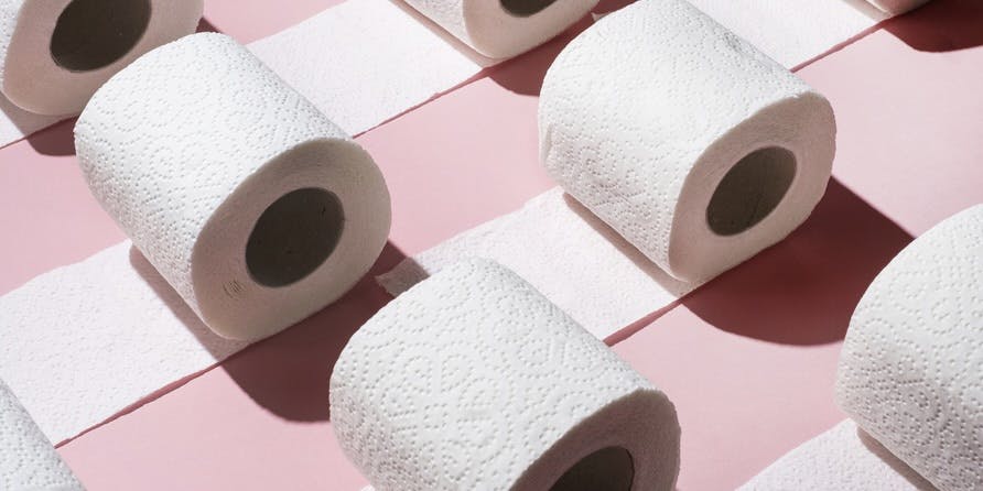 rolls of white toilet paper on a rose pink background