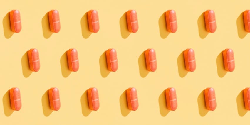 A repeating pattern of orange pills on a lemon yellow background