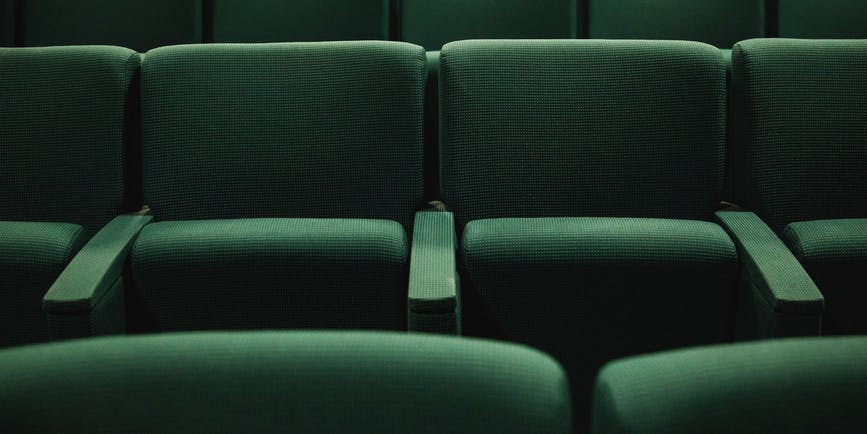 A color photograph of empty emerald green theater seats.
