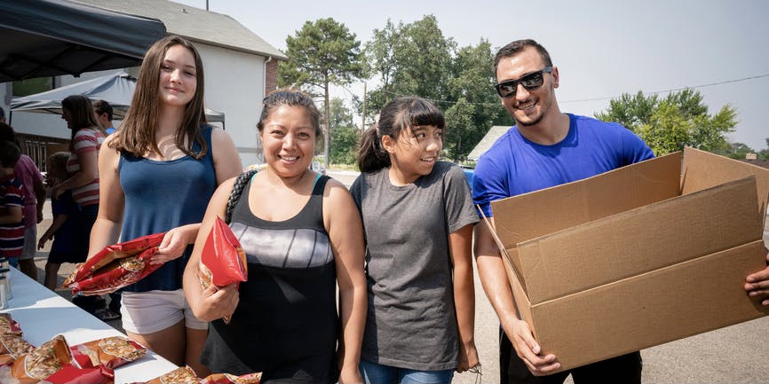 Volunteers help carry boxes of food for the recipients of a monthly church food pantry