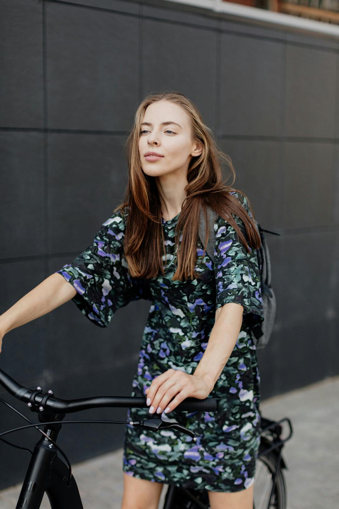 Woman in floral dress about to ride a black bicycle