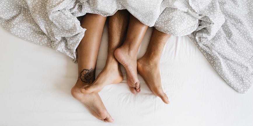 Detail of the feet of a couple lying in bed