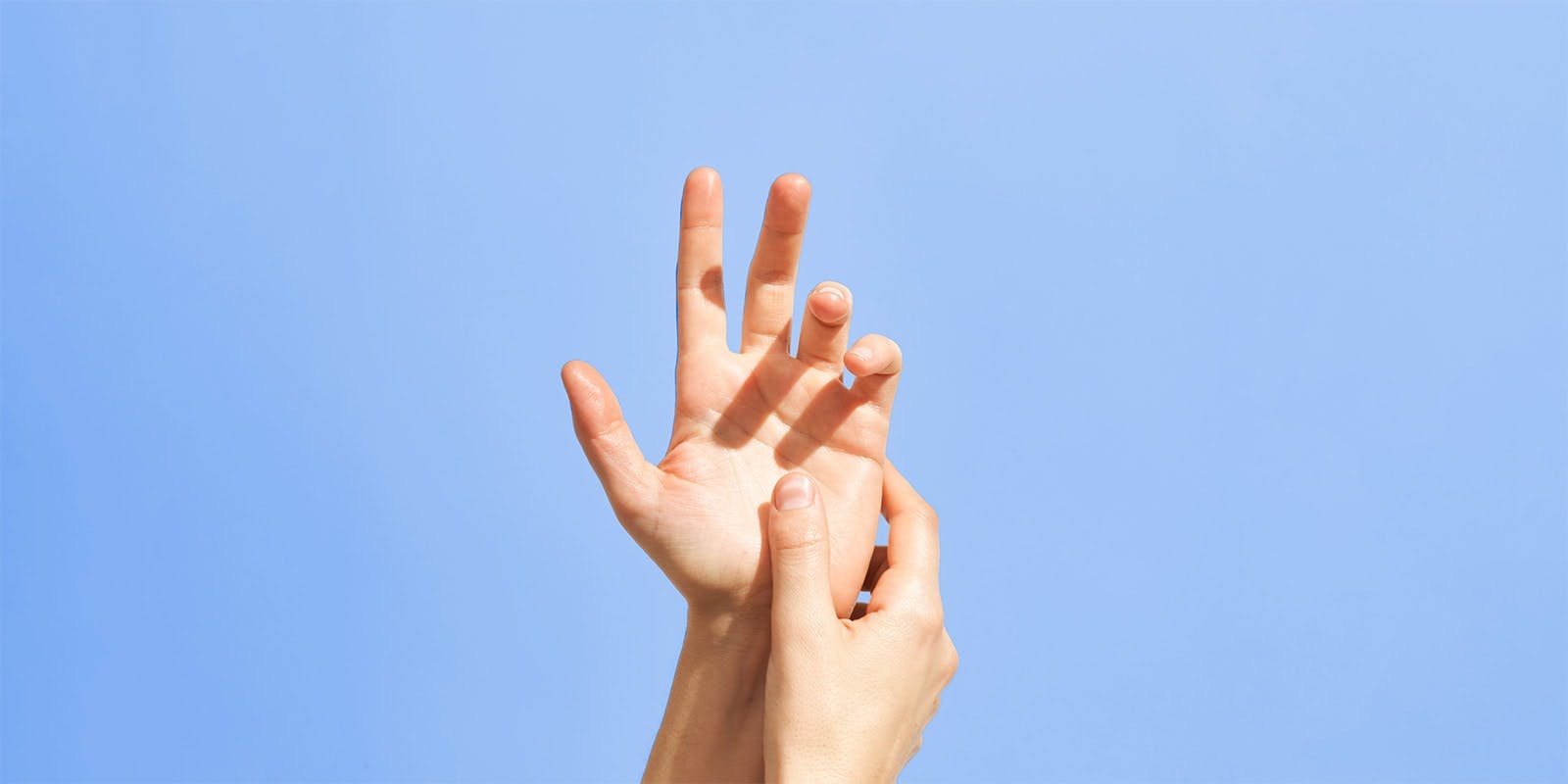 Dos manos en el aire, la derecha acariciando a la izquierda, con la palma de la izquierda mirando hacia la cámara.