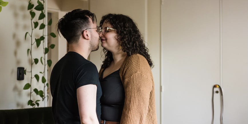 Cute curvy couple sweetly kissing at home portrait. They look real and authentic.